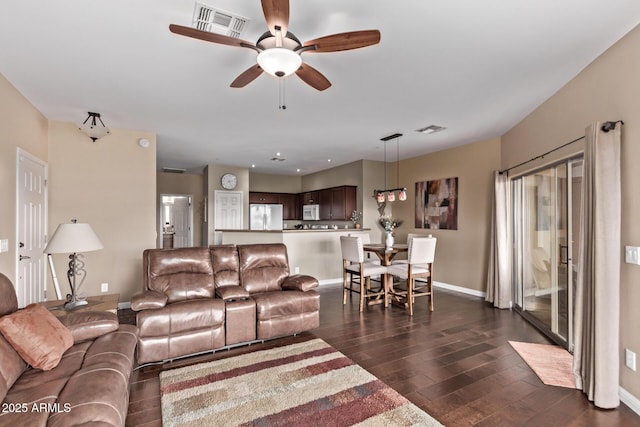 living room with dark wood-style floors, visible vents, baseboards, and ceiling fan