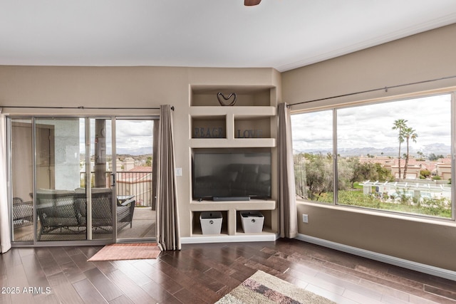 unfurnished living room with baseboards and wood finished floors