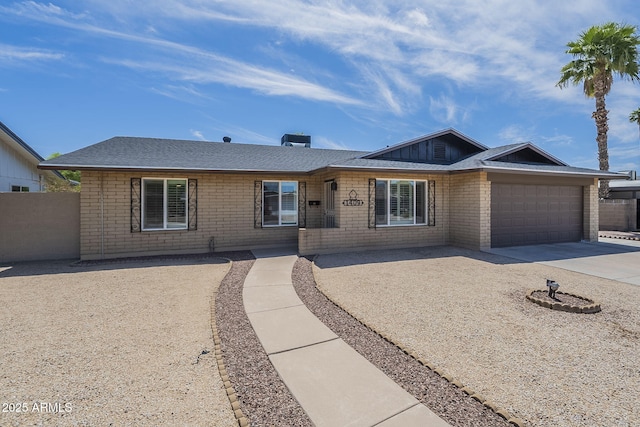 single story home featuring a garage, brick siding, fence, and concrete driveway