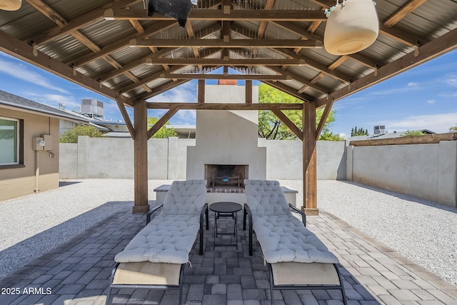 view of patio featuring a gazebo, an outdoor brick fireplace, and fence