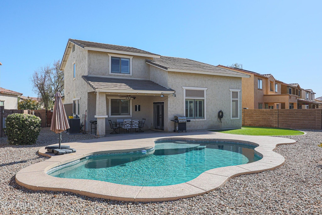 rear view of house with a patio area, central AC, and a fenced in pool