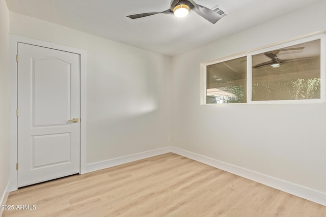 spare room with baseboards, light wood-style floors, and a ceiling fan