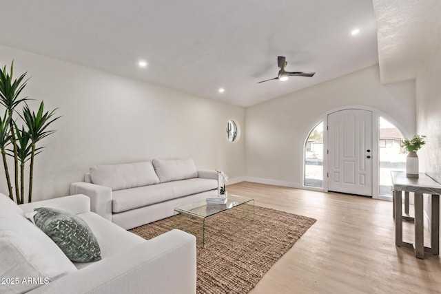 living area featuring light wood-style flooring, recessed lighting, arched walkways, baseboards, and ceiling fan