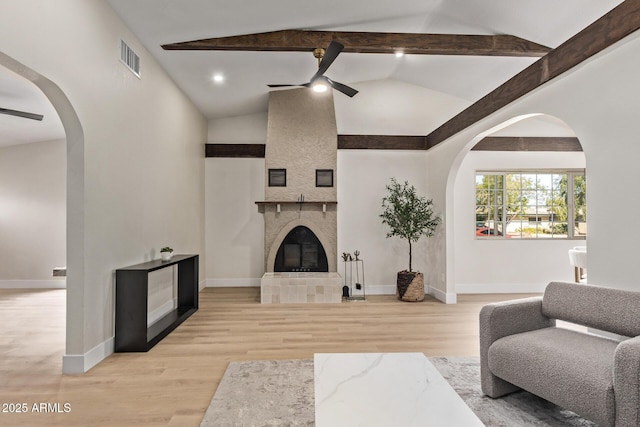 living area with lofted ceiling with beams, light wood-style flooring, ceiling fan, and a fireplace