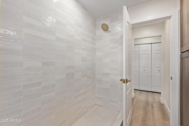 full bath featuring tiled shower and wood finished floors