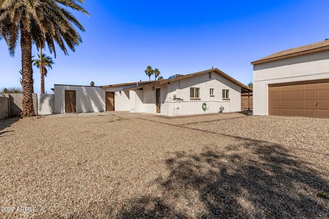 single story home featuring stucco siding, a garage, and fence