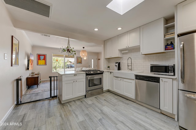 kitchen featuring white cabinets, sink, light hardwood / wood-style floors, kitchen peninsula, and appliances with stainless steel finishes