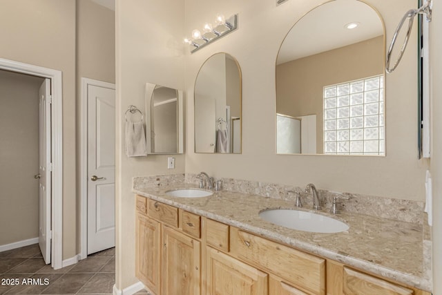 full bath featuring double vanity, a sink, baseboards, and tile patterned floors