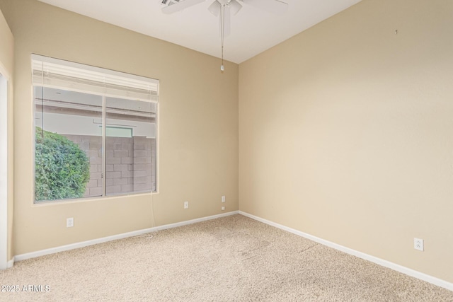 carpeted spare room featuring ceiling fan and baseboards