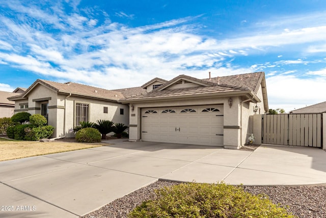 ranch-style house featuring a garage, driveway, a tiled roof, a gate, and stucco siding