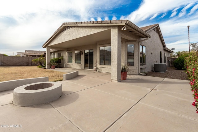 rear view of house featuring stucco siding, central air condition unit, an outdoor fire pit, a patio area, and fence