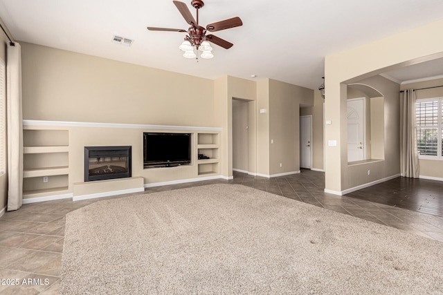 unfurnished living room featuring baseboards, visible vents, a glass covered fireplace, ceiling fan, and tile patterned floors