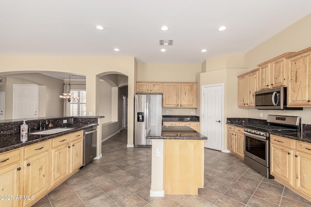 kitchen with light brown cabinets, stainless steel appliances, a kitchen island, a sink, and visible vents