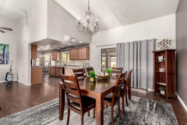 dining area with a healthy amount of sunlight, dark hardwood / wood-style flooring, ceiling fan with notable chandelier, and a high ceiling