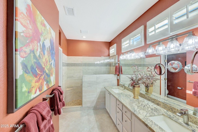 bathroom featuring tile patterned flooring, vanity, and tiled shower