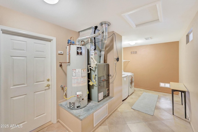 mudroom featuring light tile patterned floors, gas water heater, and washer and clothes dryer