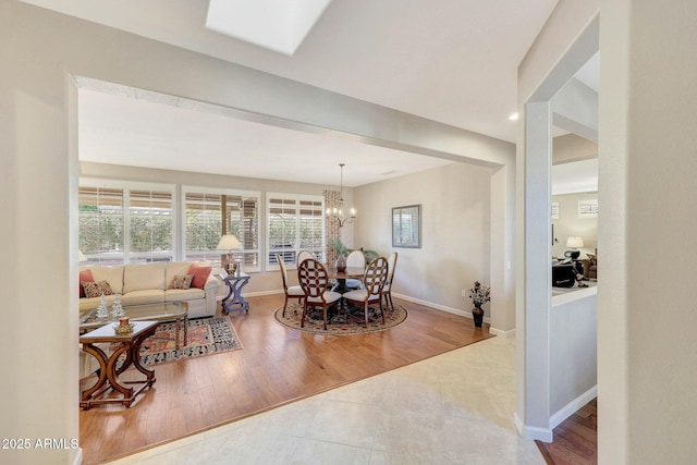 dining room featuring hardwood / wood-style floors, a skylight, and a chandelier