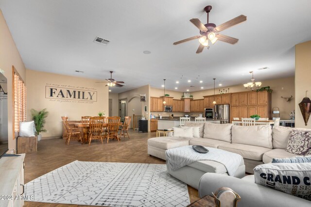 tiled living room featuring ceiling fan with notable chandelier