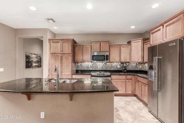 kitchen with appliances with stainless steel finishes, a sink, a breakfast bar, decorative backsplash, and recessed lighting
