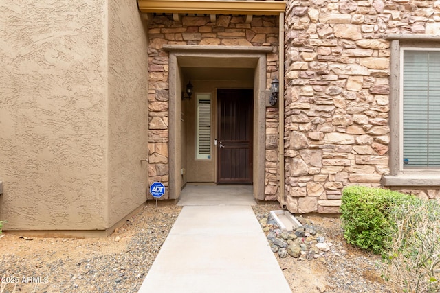 view of exterior entry featuring stucco siding and stone siding