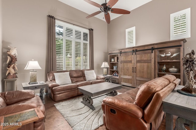 living room featuring ceiling fan, wood finished floors, and a barn door