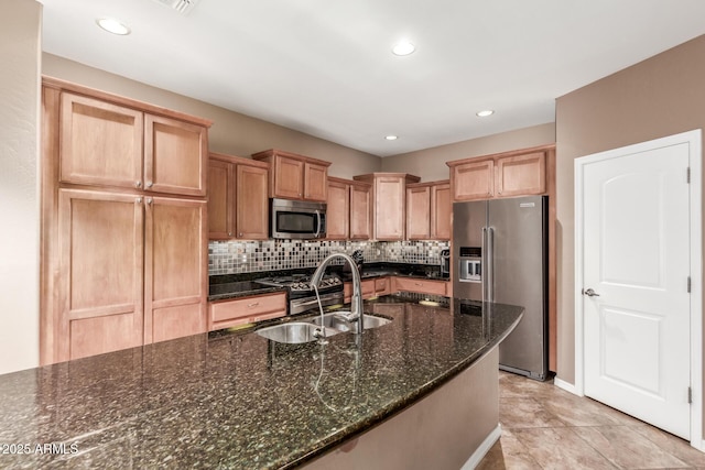 kitchen with stainless steel appliances, a sink, tasteful backsplash, dark stone countertops, and recessed lighting