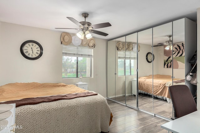 bedroom featuring a ceiling fan, a closet, baseboards, and wood finished floors