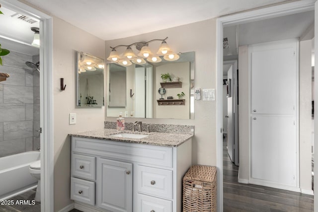 bathroom featuring visible vents, toilet, vanity, shower / tub combination, and wood finished floors