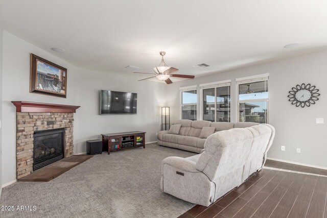 living area with baseboards, a ceiling fan, a fireplace, and dark wood-style floors