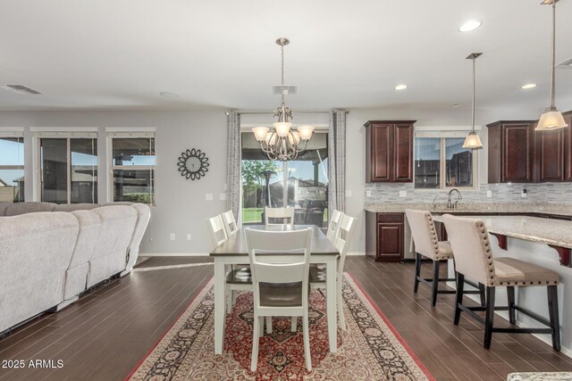 dining area featuring a chandelier, dark wood finished floors, baseboards, and recessed lighting
