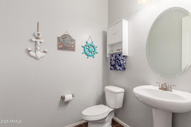 half bath with toilet, a sink, and baseboards