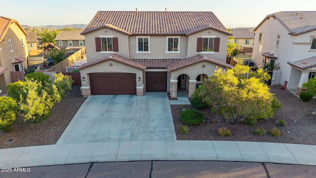 view of front facade with a tile roof, stucco siding, an attached garage, stone siding, and driveway
