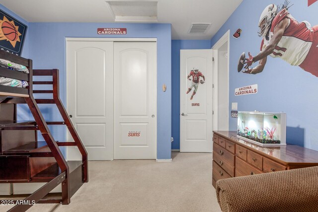 bedroom featuring a closet, light colored carpet, attic access, and baseboards