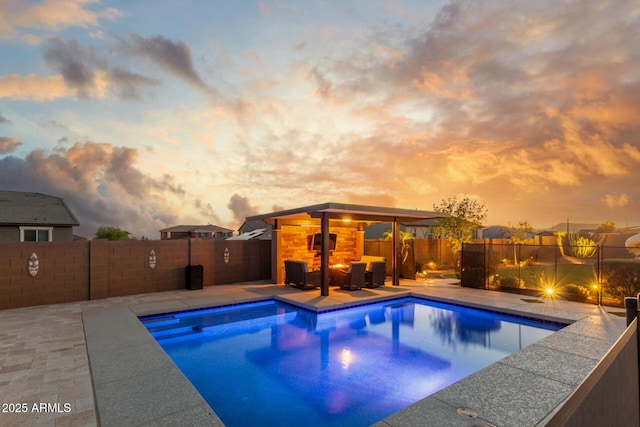 pool at dusk with a fenced backyard and a patio area