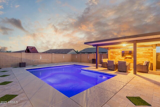pool at dusk with a patio and a fenced backyard