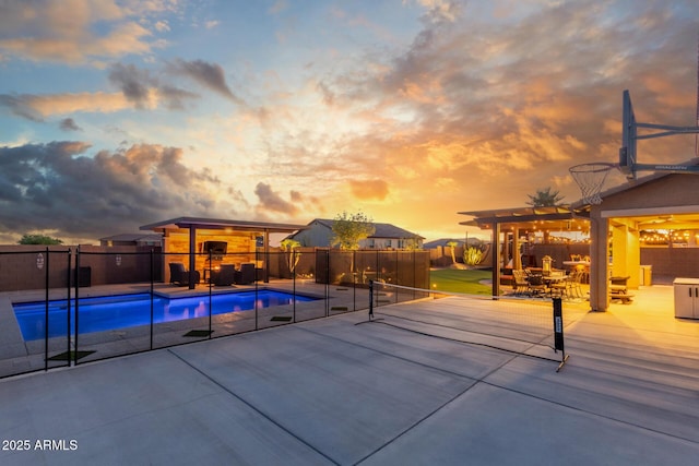 pool at dusk featuring a fenced backyard and a patio area