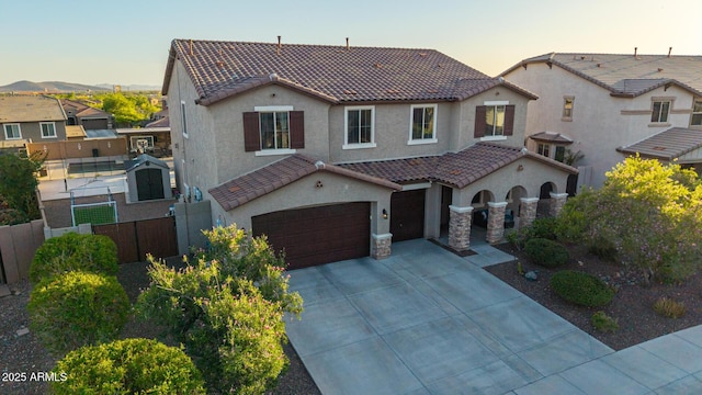 mediterranean / spanish-style house with a tiled roof, stucco siding, fence, driveway, and a garage