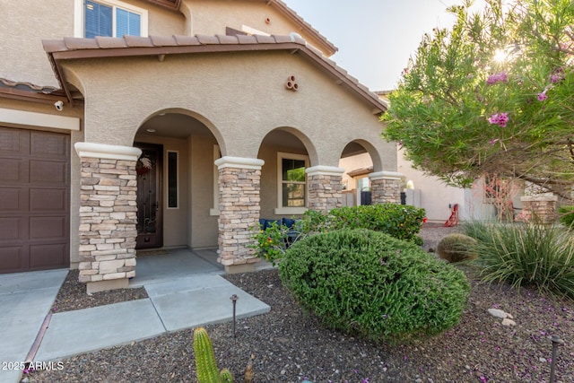 view of front of home with stucco siding, stone siding, and a garage