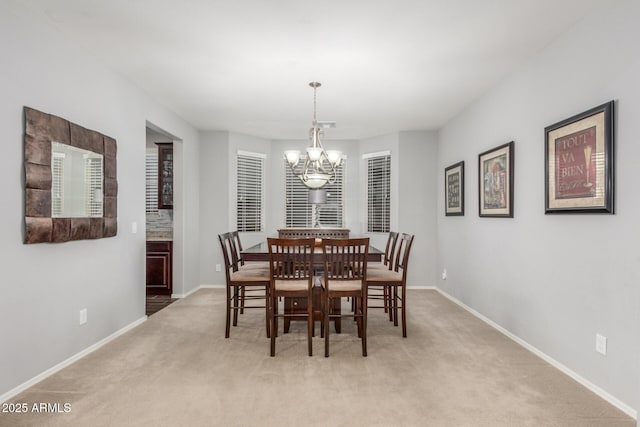 dining room with a chandelier, light carpet, and baseboards