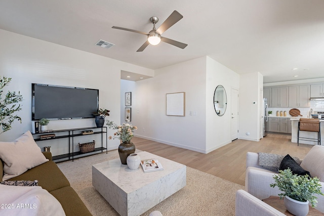 living area featuring ceiling fan, light wood finished floors, baseboards, and recessed lighting
