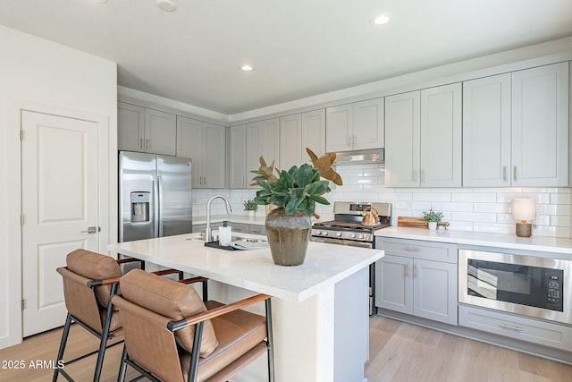 kitchen featuring stainless steel appliances, gray cabinetry, under cabinet range hood, light countertops, and recessed lighting
