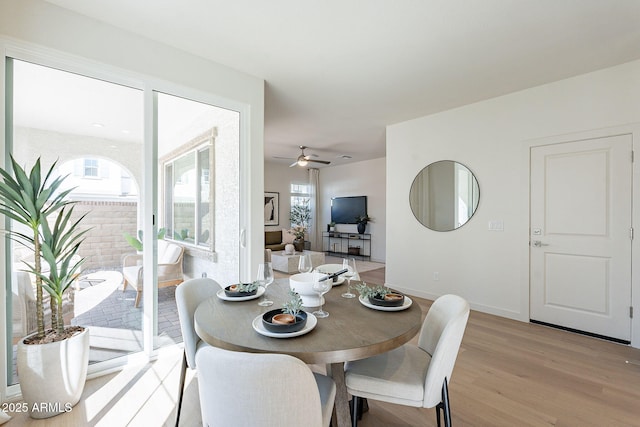 dining room with light wood finished floors, healthy amount of natural light, ceiling fan, and baseboards