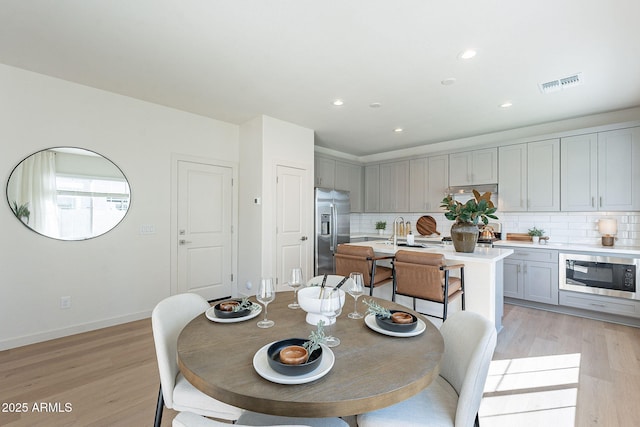 dining room with light wood finished floors, recessed lighting, and baseboards
