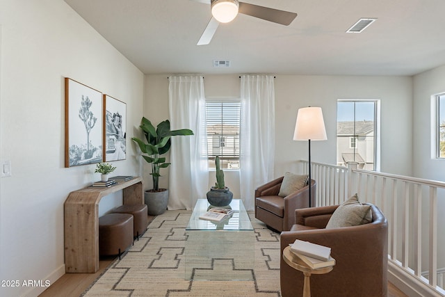 sitting room featuring healthy amount of natural light, ceiling fan, baseboards, and wood finished floors