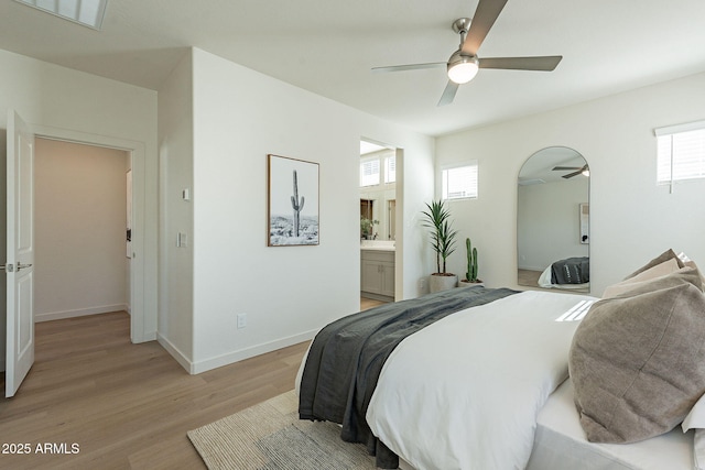 bedroom with light wood-type flooring, baseboards, ensuite bathroom, and a ceiling fan