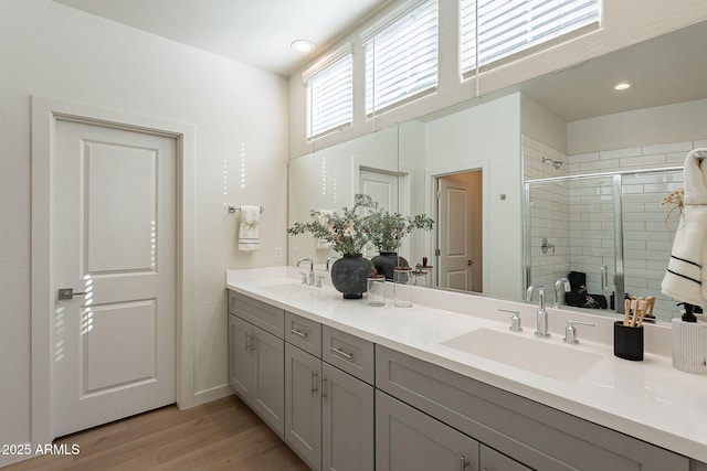full bathroom featuring wood finished floors, a stall shower, double vanity, recessed lighting, and baseboards
