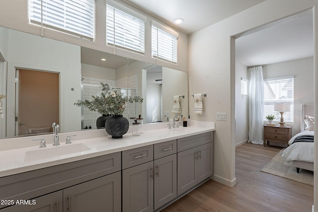full bathroom with healthy amount of natural light, wood finished floors, a stall shower, and double vanity