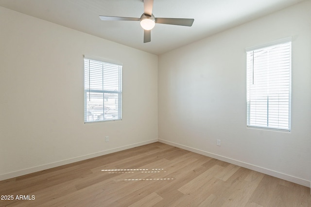 empty room featuring light wood-style flooring, plenty of natural light, baseboards, and a ceiling fan