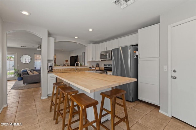 1703 E Palo Blanco Way, Gilbert, AZ 85296 - kitchen featuring stainless steel appliances, light tile patterned flooring, arched walkways, a breakfast bar, and a ceiling fan