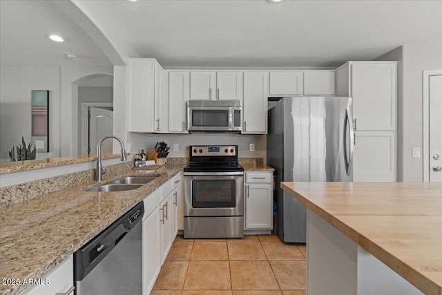 1703 E Palo Blanco Way, Gilbert, AZ 85296 - kitchen with appliances with stainless steel finishes, a sink, white cabinetry, light stone counters, and arched walkways